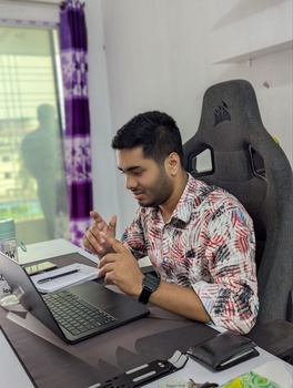 man sitting at a desk using a laptop and gesturing during a video call