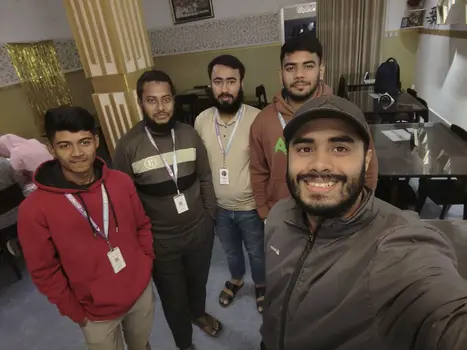 group selfie of five men wearing id badges in an office