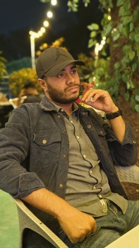 man sitting outdoors at night under string lights looking thoughtful